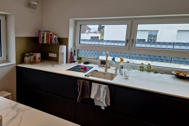 moderne Häcker Küche, Spülbecken und Arbeitsfläche in Marmoroptik, mattschwarze Fronten, Armatur gold