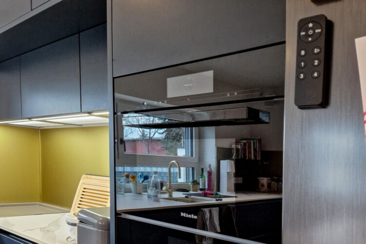 moderne Häcker Küche, mattschwarz, schwarze Miele Einbaugeräte, Küchenplatte in Marmoroptik