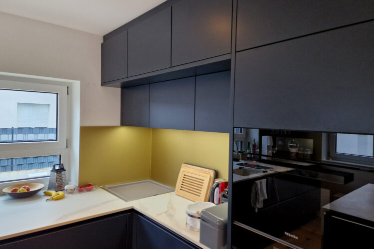 moderne Häcker Küche, mattschwarze Fronten, Arbeitsplatte in Marmoroptik, Hochschränke, integrierte Beleuchtung, Miele Geräte schwarz, integriertes Fach für die Küchenmaschine