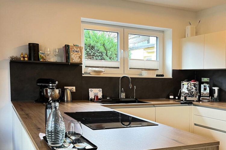Expressküche weiß matt, Arbeitsfläche in Holzoptik, U-förmige Küche mit moderner Kochplatte und Multifunktionsspüle in schwarz